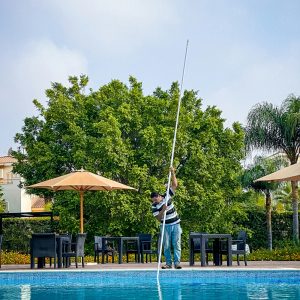 Técnico limpiando el fondo de una piscina con pértiga