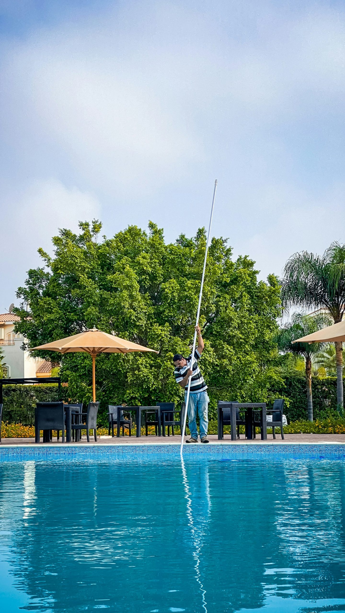 Técnico limpiando el fondo de una piscina con pértiga